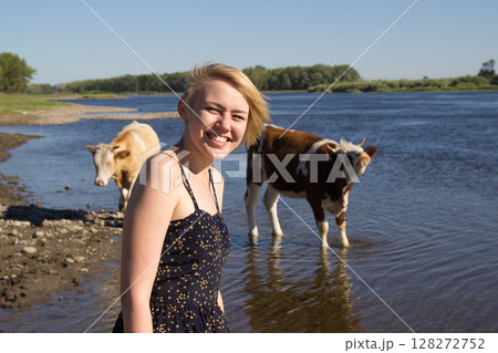 Girl Smiling by a River With Cows During a Sunny Day in a Rural Area Girl Smiling by a River With Cows During a Sunny Day in a Rural Area 128272752