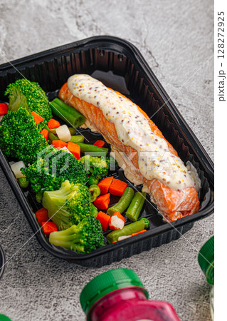 Salmon with sauce and vegetables in container Salmon with sauce and vegetables in container 128272925