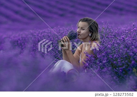A woman is sitting in a field of purple flowers A woman is sitting in a field of purple flowers 128273502