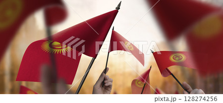 Kirghizia flags in their hands on a blurred urban background 128274256