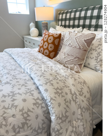 Chic bedroom design with a white and gray floral comforter and bright decorative pillows. Great for retail furniture marketing or digital mood boards. Chic bedroom design with a white and gray floral comforter and bright decorative pillows. Great for retail furniture marketing or digital mood boards. 128274904
