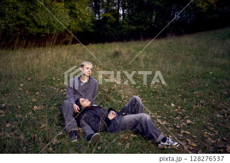 15-year-old teenage couple in love lies, sits on the grass in the park surrounded by fallen autumn leaves 128276537
