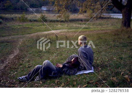 15-year-old teenage couple in love lies, sits on the grass in the park surrounded by fallen autumn leaves 15-year-old teenage couple in love lies, sits on the grass in the park surrounded by fallen autumn leaves 128276538