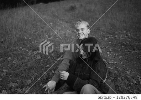 15-year-old teenage couple in love lies, sits on the grass in the park surrounded by fallen autumn leaves 128276549
