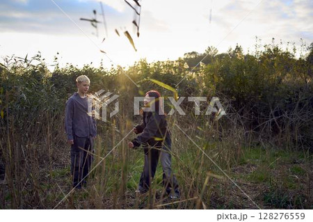 15-year-old teenage couple in love playing in  reeds at sunset 128276559