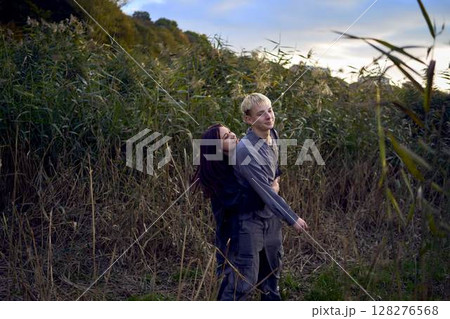 15-year-old teenage couple in love playing in reeds at sunset 15-year-old teenage couple in love playing in reeds at sunset 128276568