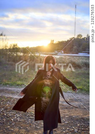 a 15-year-old teenage girl in a black long coat at sunset by the river a 15-year-old teenage girl in a black long coat at sunset by the river 128276583