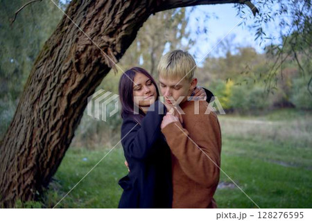 15-year-old teenage couple in love walks through the park on a cold autumn evening 128276595