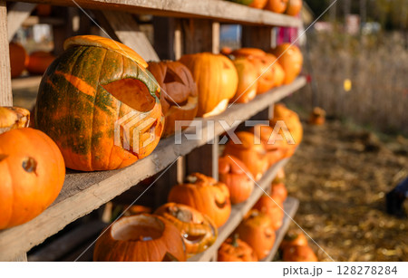 Funny carved Halloween pumpkins on wooden shelf at autumn festival 128278284