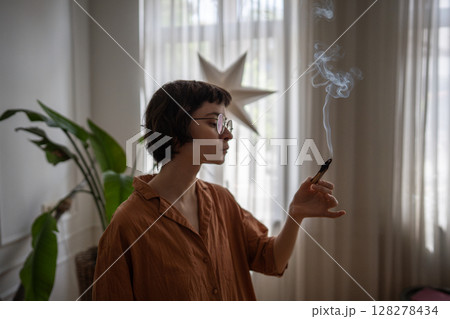 Calm woman light palo santo stick, fill air with fragrant smoke for mental wellbeing. Small rituals 128278434