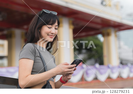 Happy young southeast asian woman teenager blogger searching travel map guide on smartphone for local cultural tourism experience in Bangkok Thailand for world travel in Asia 128279231