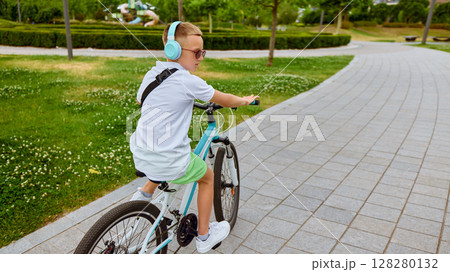 Morning flow. Boy cycling with headphones in park on sunny day 128280132