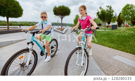 Wheels and words. Children enjoying a sunny day biking in the park 128280133