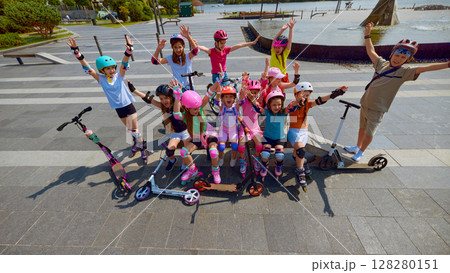 Group of children celebrating with scooters in sunny urban park 128280151