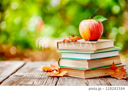 Red apple on stack of books on wooden table with blurred bokeh background Red apple on stack of books on wooden table with blurred bokeh background 128281584