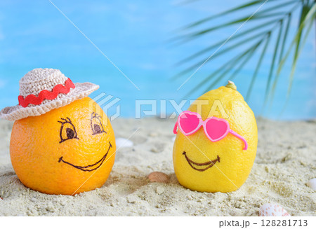 Creative minimal summer idea. Citrus hipster. Orange in bamboo hat and lemon in sunglasses on sand. Tropical beach concept. Creative art. Fun party Mood. Copy space 128281713