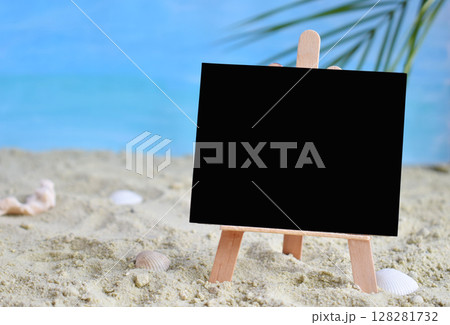 Creative minimal summer idea. Blackboard on sand with blur blue sea and tropical palm leaf. Vacation promotion sale concept. Creative art. Copy space Creative minimal summer idea. Blackboard on sand with blur blue sea and tropical palm leaf. Vacation promotion sale concept. Creative art. Copy space 128281732