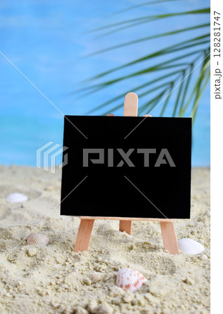 Creative minimal summer idea. Blackboard on sand with blur blue sea and tropical palm leaf. Vacation promotion sale concept. Creative art. Copy space Creative minimal summer idea. Blackboard on sand with blur blue sea and tropical palm leaf. Vacation promotion sale concept. Creative art. Copy space 128281747