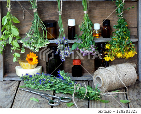 bunches of healing herbs - mint, yarrow, lavender, clover, hyssop, milfoil, mortar with flowers of calendula and bottles, herbal medicine 128281825