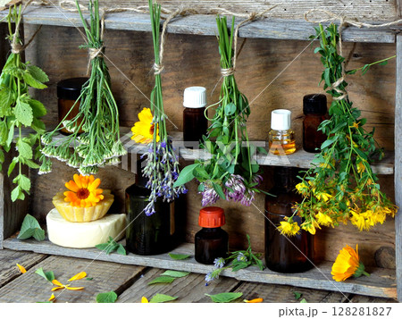 bunches of healing herbs - mint, yarrow, lavender, clover, hyssop, milfoil, mortar with flowers of calendula and bottles, herbal medicine 128281827