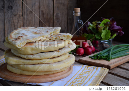 Pile of homemade flat bread with lettuce, onion and radish on a wooden background. Mexican flatbread taco. Indian Naan. Space for text Pile of homemade flat bread with lettuce, onion and radish on a wooden background. Mexican flatbread taco. Indian Naan. Space for text 128281991