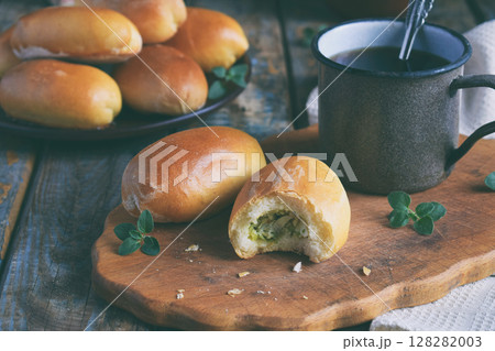 Pies with cabbage and eggs. Baked stuffed patties and cup of tea. Rustic photo. Copy space Pies with cabbage and eggs. Baked stuffed patties and cup of tea. Rustic photo. Copy space 128282003