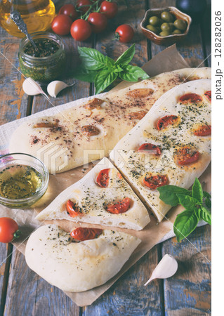 Traditional Italian Focaccia with tomatoes, basil, garlic and sumach. Homemade pastry. Flat bread. Organic flatbread. Rustic style. Traditional Italian Focaccia with tomatoes, basil, garlic and sumach. Homemade pastry. Flat bread. Organic flatbread. Rustic style. 128282026