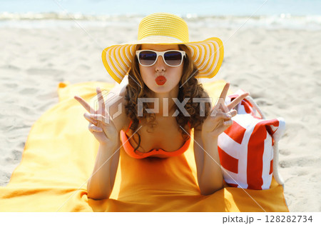 Summer vacation, happy young woman in tourist hat with sunglasses lying on sea beach Summer vacation, happy young woman in tourist hat with sunglasses lying on sea beach 128282734