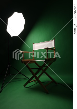 Chair of Film Director. Directors chair in green screen studio setup with softbox lighting. Ideal for filmmaking video production photo interviews and creative content with green chroma key background Chair of Film Director. Directors chair in green screen studio setup with softbox lighting. Ideal for filmmaking video production photo interviews and creative content with green chroma key background 128282846