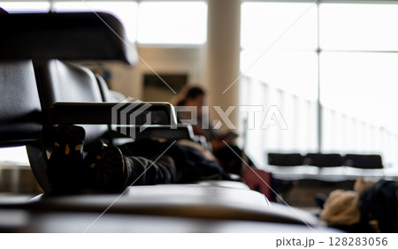 Selective focus on the feet of a child asleep on a row of chairs in an airplane terminal Selective focus on the feet of a child asleep on a row of chairs in an airplane terminal 128283056
