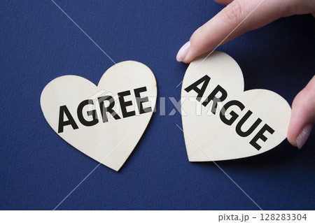 Agree or Argue symbol. Concept word Agree or Argue on wooden hearts. Businessman hand. Beautiful deep blue background. Business and Agree or Argue concept. Copy space 128283304