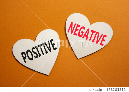 Positive or Negative symbol. Concept word Positive or Negative on wooden hearts. Beautiful orange background. Business and Positive or Negative concept. Copy space Positive or Negative symbol. Concept word Positive or Negative on wooden hearts. Beautiful orange background. Business and Positive or Negative concept. Copy space 128283311