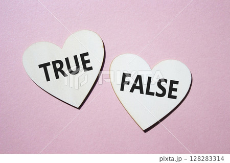 True or False symbol. Concept word True or False on wooden hearts. Beautiful pink background. Business and True or False concept. Copy space 128283314