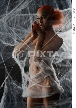 Red woman caught in an intricate net trap surrounded by webs at night Red woman caught in an intricate net trap surrounded by webs at night 128283468