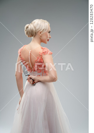 Bride in elegant dress with a hidden weapon and an eerie ambiance Bride in elegant dress with a hidden weapon and an eerie ambiance 128283470
