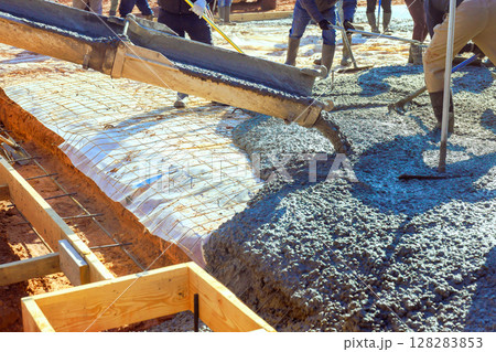 Construction workers skillfully pour wet concrete into foundation form while to foundation slab Construction workers skillfully pour wet concrete into foundation form while to foundation slab 128283853