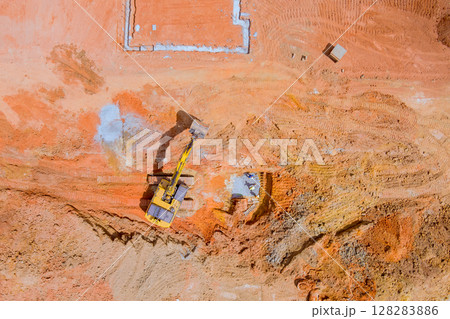 Excavator is digging moving earth on construction site preparing for foundations under works day 128283886