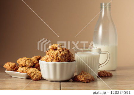 Oatmeal cookies and milk sit on a kitchen table. 128284591