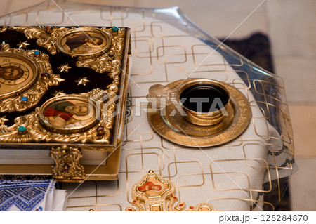 Orthodox Religious Artifacts Still Life: Vintage Book, Candleholder, and Incense Burner on White Fabric Background, Golden Tones 128284870