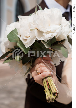 Elegant Wedding Bouquet with White Peonies and Eucalyptus Held by a Groomsman in Traditional Formal Attire, Soft Lighting Elegant Wedding Bouquet with White Peonies and Eucalyptus Held by a Groomsman in Traditional Formal Attire, Soft Lighting 128284877