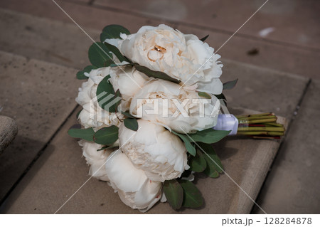 Elegant Wedding Rings on a White Peony Bouquet with Eucalyptus Leaves. Romance, Celebration, Bridal Flowers, Soft Focus, Beige Background Elegant Wedding Rings on a White Peony Bouquet with Eucalyptus Leaves. Romance, Celebration, Bridal Flowers, Soft Focus, Beige Background 128284878