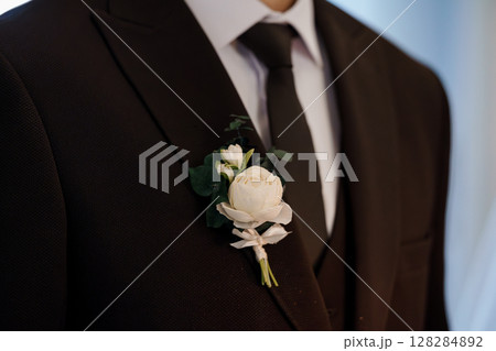 Elegant Groom Boutonniere Detail: Black Suit Lapel with Cream Rose, Eucalyptus, Ribbon, Wedding Formal Wear, Close-Up Fashion Photography. 128284892