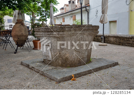 Ancient stone well with carved reliefs in Motovun, Croatia. 128285134