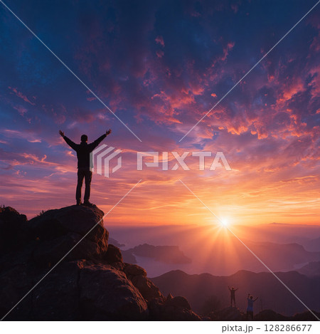 Sunrise over mountains as a person celebrates the beginning of a new day with arms raised 128286677