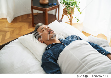 寝室のベッドで眠る50代のミドル男性 寝室のベッドで眠る50代のミドル男性 128287454