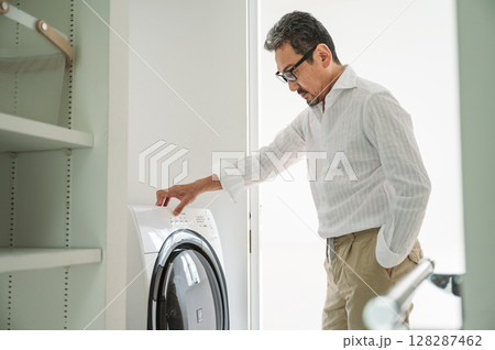 ドラム式洗濯機で服を洗う50代のミドル男性 128287462