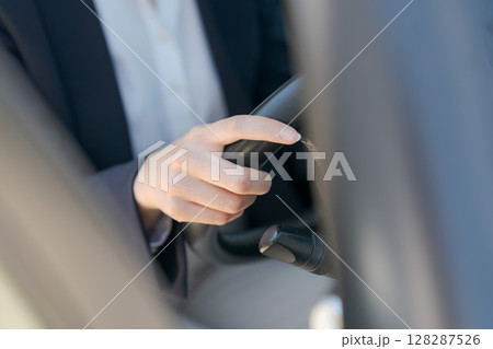車のハンドルを握る女性の手元 128287526