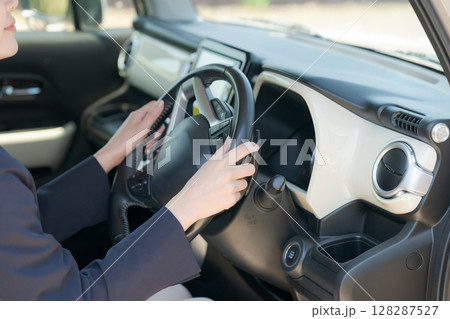 車のハンドルを握る女性の手元 128287527