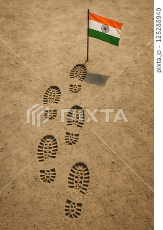 Top view of army boot prints leading to a lone Indian flag on dusty ground 128288940