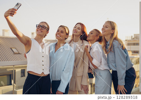 A group of friends happily taking a joyful selfie together on a rooftop during sunset time A group of friends happily taking a joyful selfie together on a rooftop during sunset time 128289318
